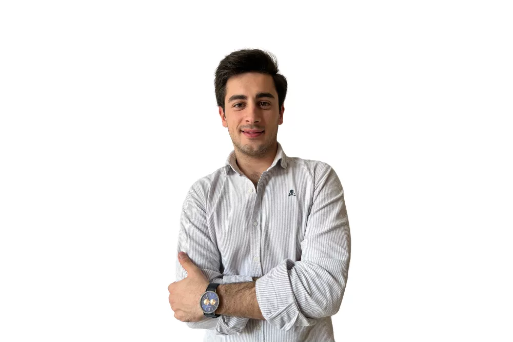 Hombre sonriendo con brazos cruzados, fondo blanco.