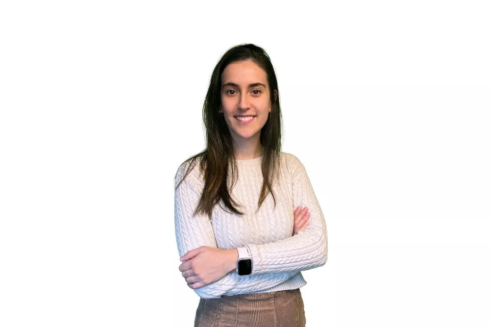 Mujer sonriendo con brazos cruzados, fondo blanco.